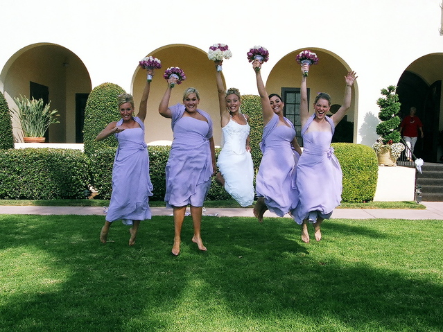 Bride and bridesmaids jumping in the air in a grassy area